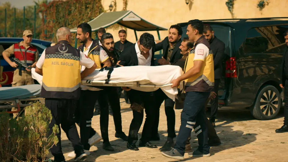41. bölüm fragmanından kare: sağlık görevlileri ve takım elbiseli erkekler bir sedyeyi taşıyor.